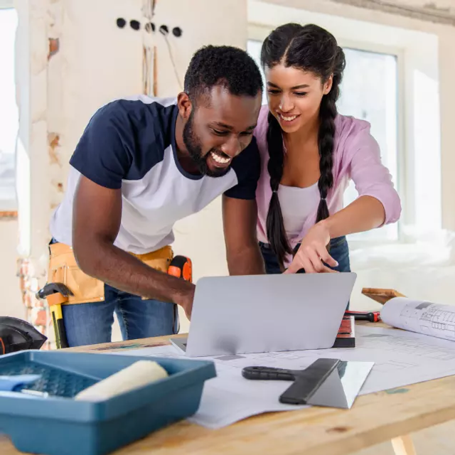 Laughing couple looking at a laptop computer absolutely loving the price increase HonestDoor will give them after they measure all the studs and confirm they are all the same size